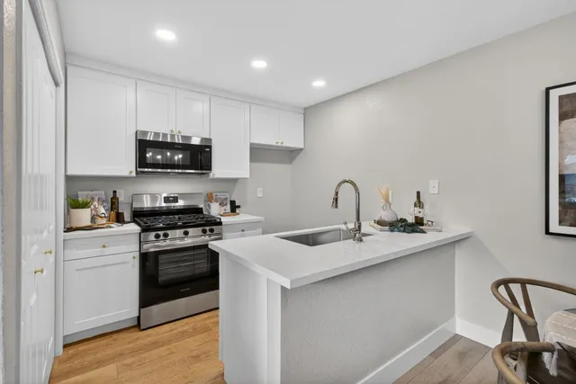 a kitchen with stainless steel appliances a sink a stove top oven a counter space and cabinets