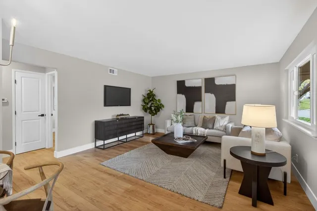 a living room with furniture a flat screen tv and a window