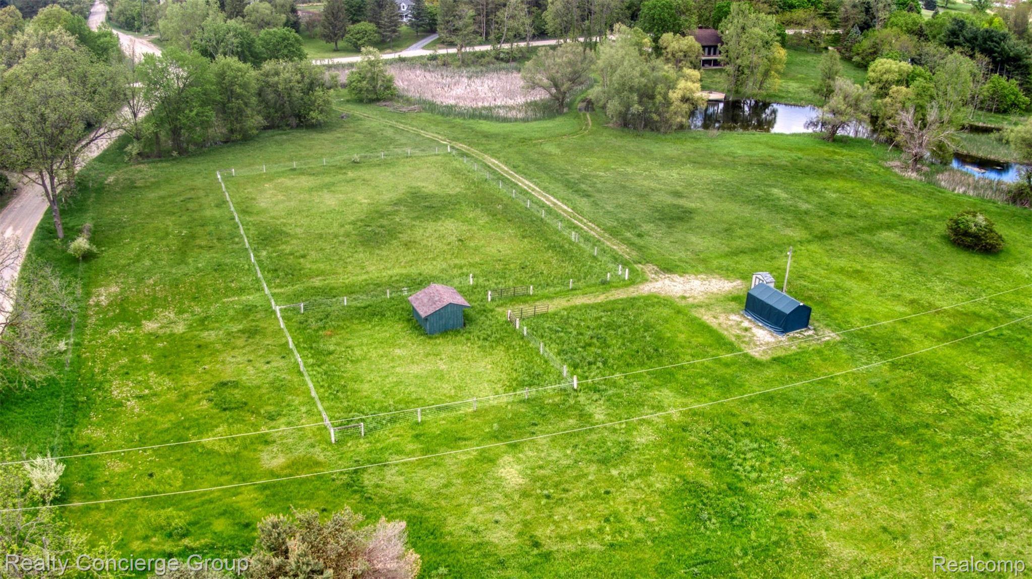 2110 East Clyde Road Howell, MI 48855 - Photo 44 of 44 Drone views of the 11 acre property; including private pond, connecting driveway to pastures, sheds and electric fencing