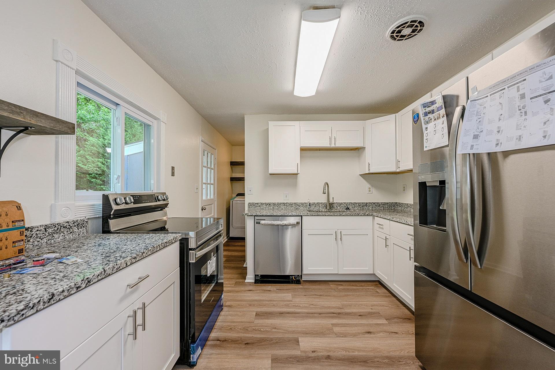 6728 Bowie Drive Springfield, VA 22150 - Photo 9 of 26 a kitchen with granite countertop stainless steel appliances a refrigerator cabinets and wooden floor
