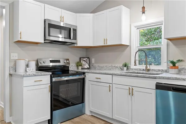 a kitchen with granite countertop white cabinets and white appliances