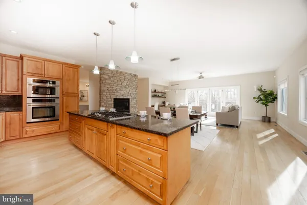 a large kitchen with stainless steel appliances granite countertop a stove and a wooden floors