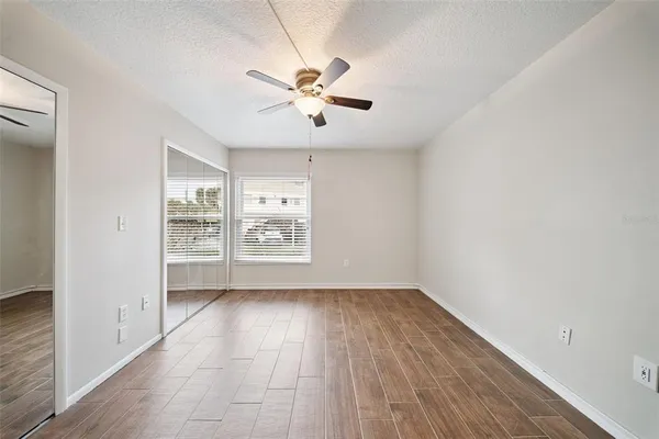 an empty room with windows and fan