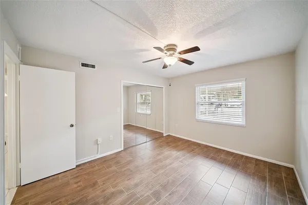 a view of an empty room with a window and wooden floor