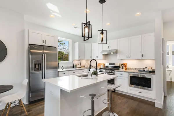 a kitchen with stainless steel appliances a stove a sink a refrigerator a stove a microwave and cabinets