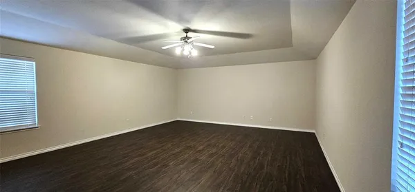 an empty room with wooden floor chandelier fan and windows