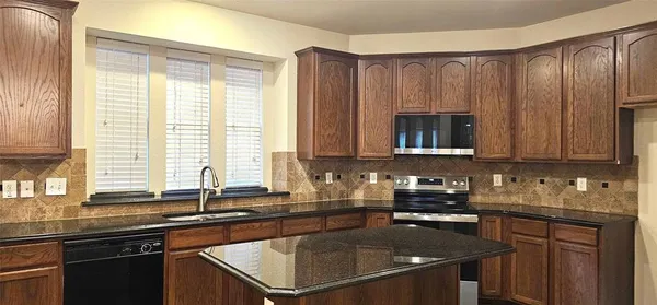 a kitchen with granite countertop a sink a stove and cabinets