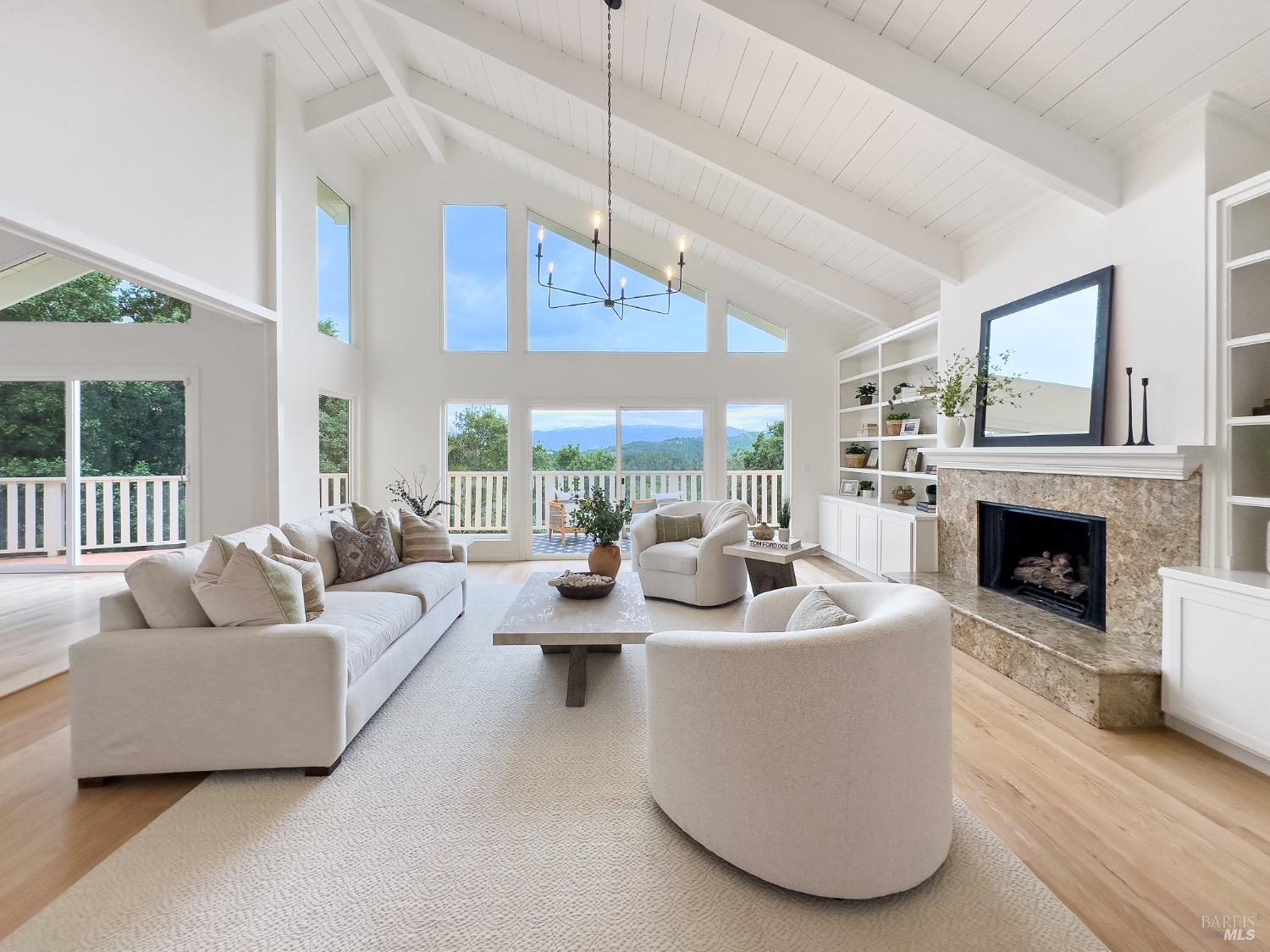 Dramatic and grand living room with cathedral ceiling, fireplace and a deck to enjoy the spectacular views. There are hardwood floors throughout the home