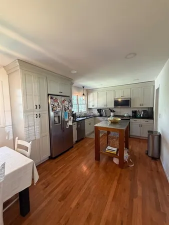 a living room with stainless steel appliances kitchen island granite countertop furniture and a wooden floor