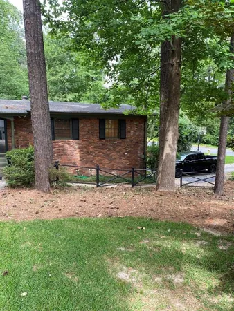 a backyard of a house with table and chairs under an large tree