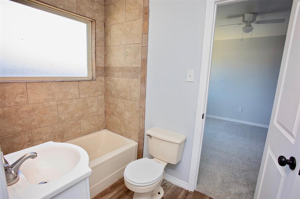 1214 3rd Street Graham, TX 76450 - Photo 18 of 23 a white toilet sitting next to a bathroom sink and tub