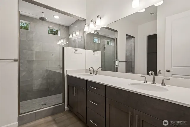 a bathroom with a double vanity sink mirror and shower