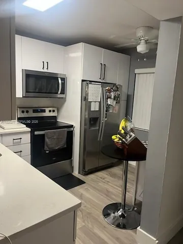 a kitchen with stainless steel appliances a stove refrigerator and microwave with wooden floor