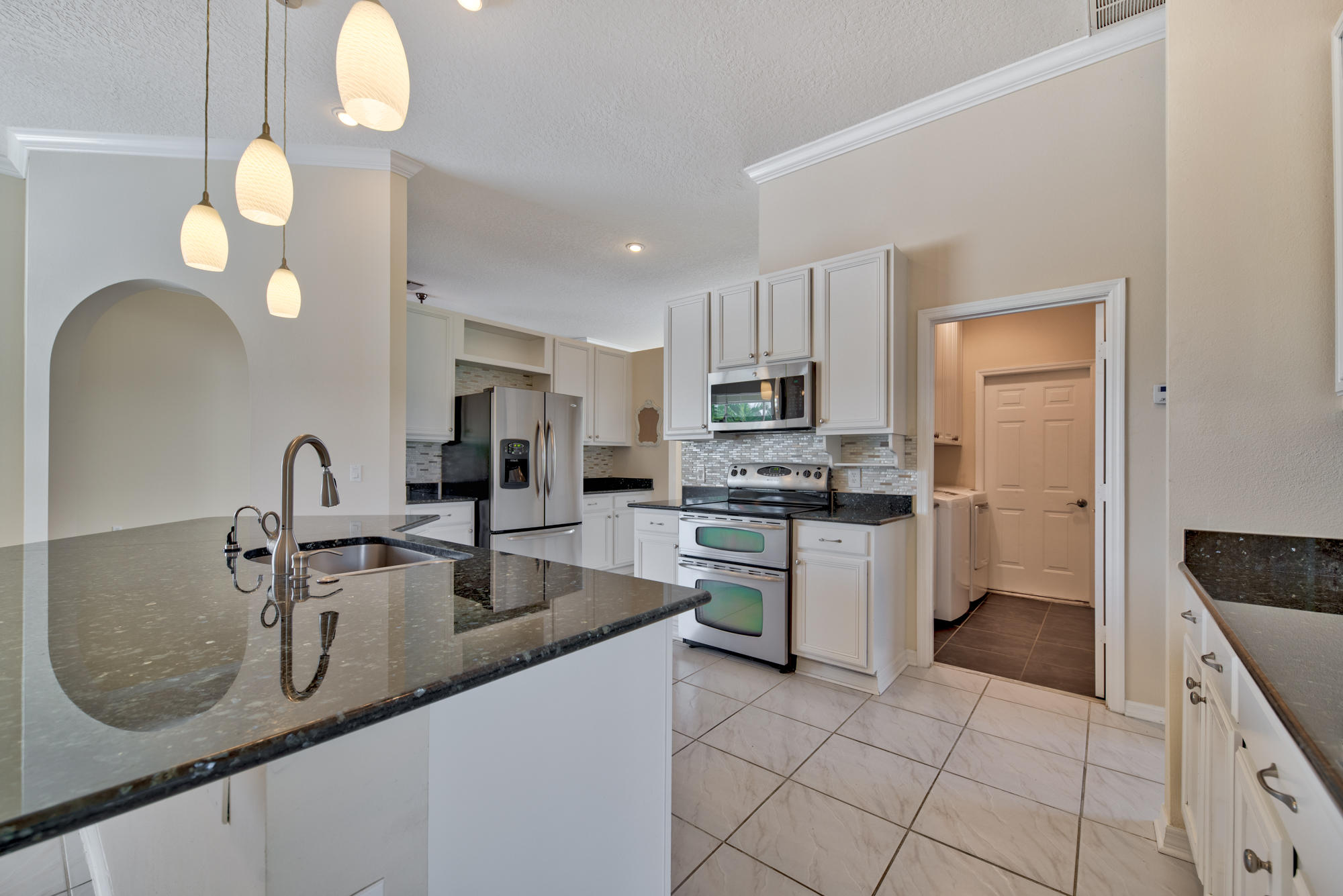 567 Southwest Spring Hill Point Port St. Lucie, FL 34986 - Photo 9 of 36 a kitchen with kitchen island granite countertop a sink a counter top space appliances and cabinets
