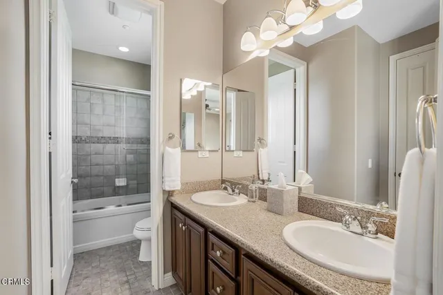 a bathroom with a granite countertop sink a toilet a mirror and shower