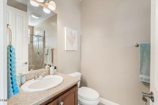 a bathroom with a granite countertop sink a toilet and a mirror
