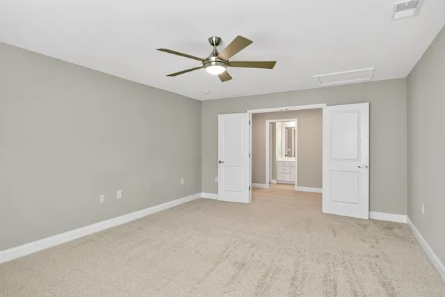 a view of an empty room with chandelier fan