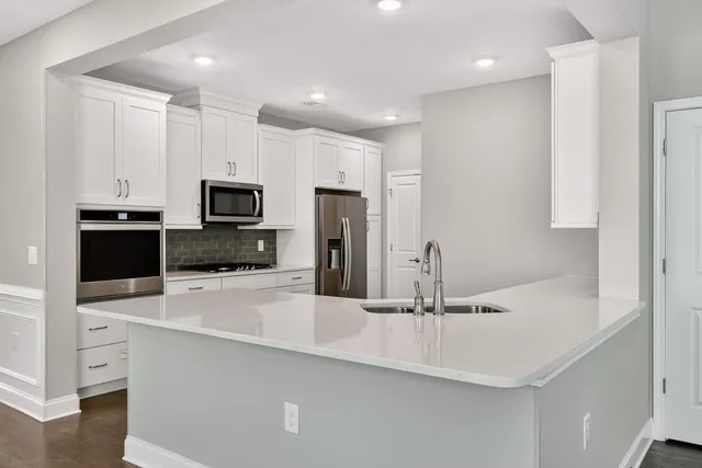 a kitchen with stainless steel appliances a sink a stove a microwave and island