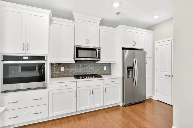 a kitchen with white cabinets and stainless steel appliances