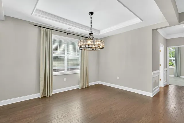 an empty room with wooden floor closet and windows