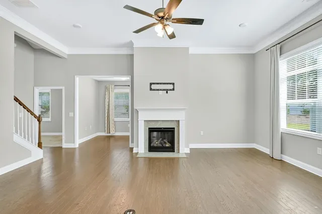 a view of an empty room with wooden floor fireplace and a window