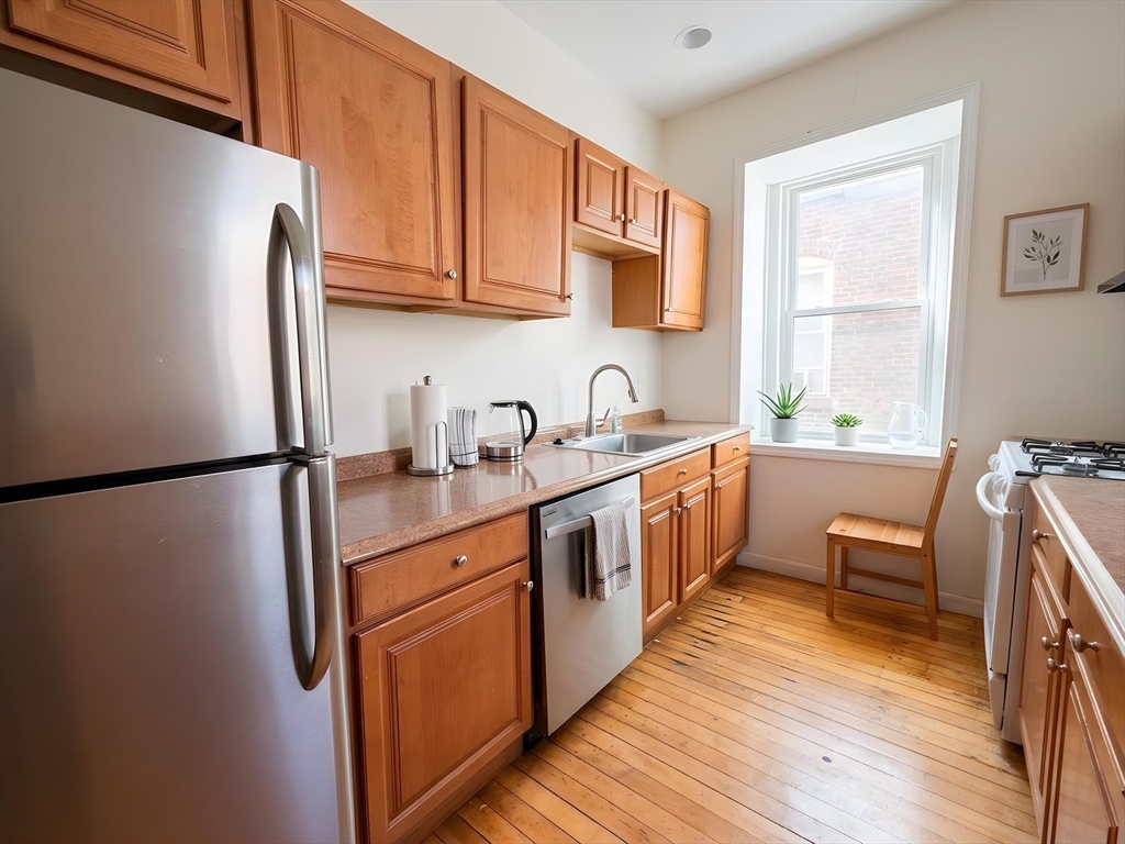 a kitchen with stainless steel appliances granite countertop a refrigerator a sink dishwasher a stove with wooden floor