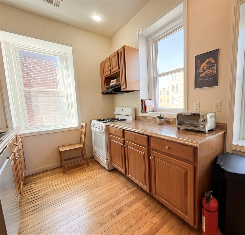 11 Vancouver Street, Unit 2 Boston, MA 02115 - Photo 5 of 14 a kitchen with a sink cabinets wooden floor and a window