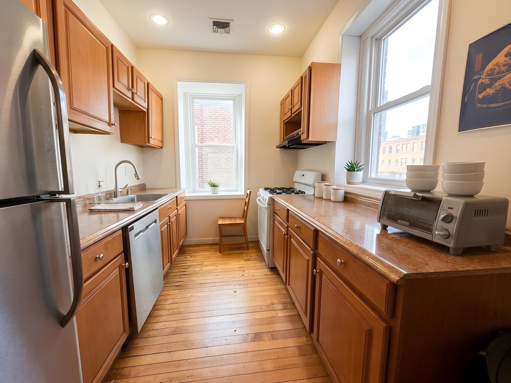 11 Vancouver Street, Unit 2 Boston, MA 02115 - Photo 6 of 14 a kitchen with granite countertop a sink wooden floor and stainless steel appliances