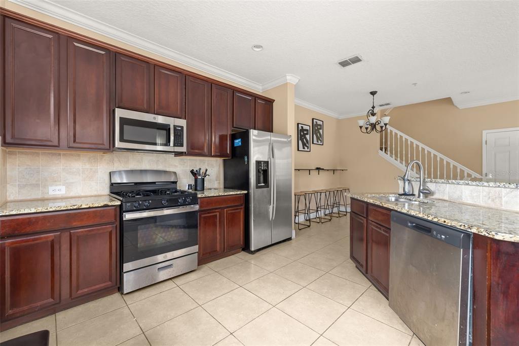 811 Assembly Court Reunion, FL 34747 - Photo 14 of 84 a kitchen with granite countertop a stove top oven microwave and refrigerator