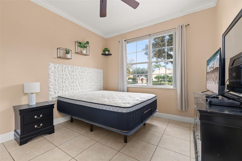 811 Assembly Court Reunion, FL 34747 - Photo 18 of 84 a bedroom with a bed and a flat tv screen on a dresser