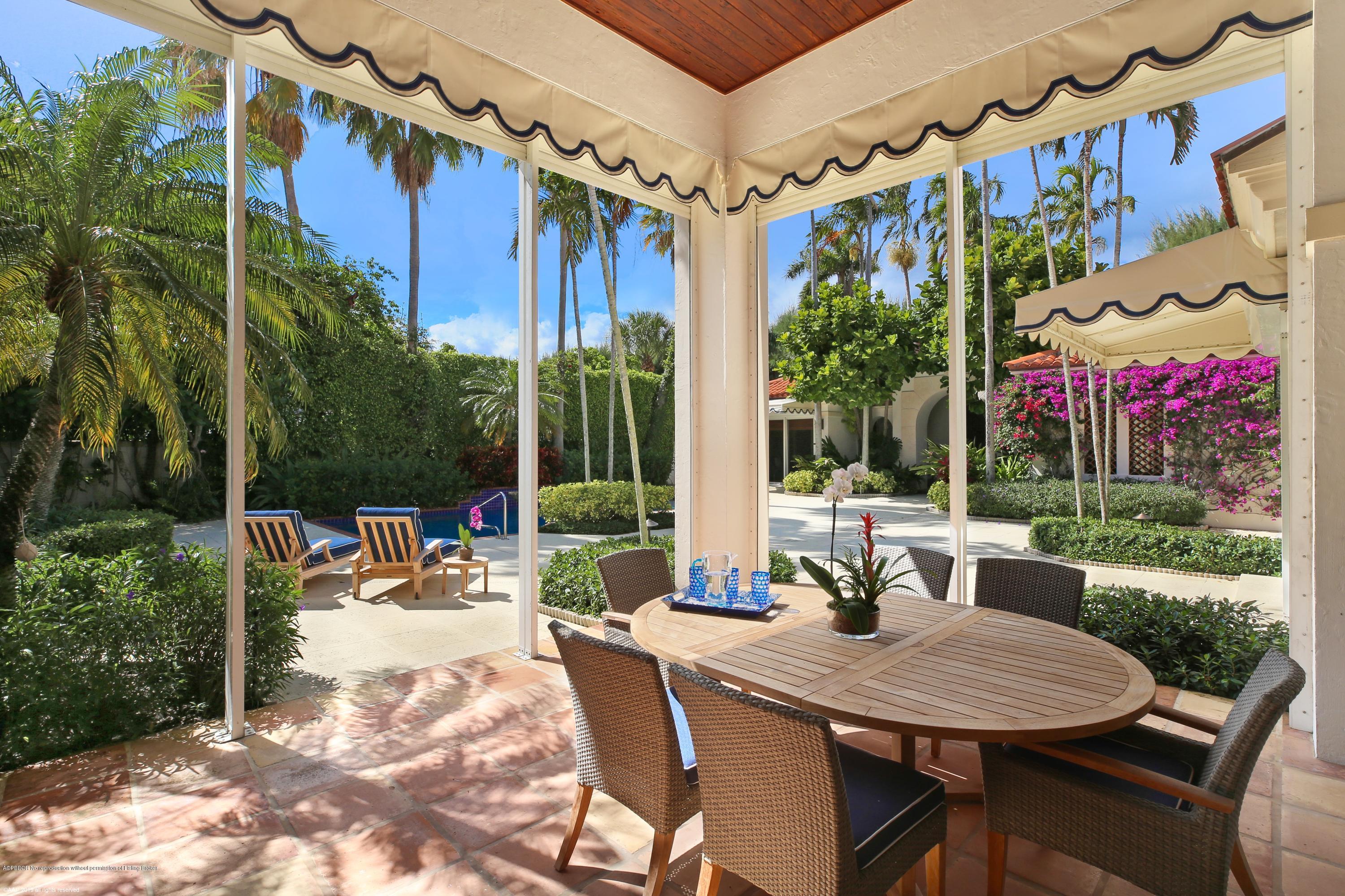 210 Wells Road Palm Beach, FL 33480 - Photo 25 of 65 a view of a patio with a table chairs and a floor to ceiling window