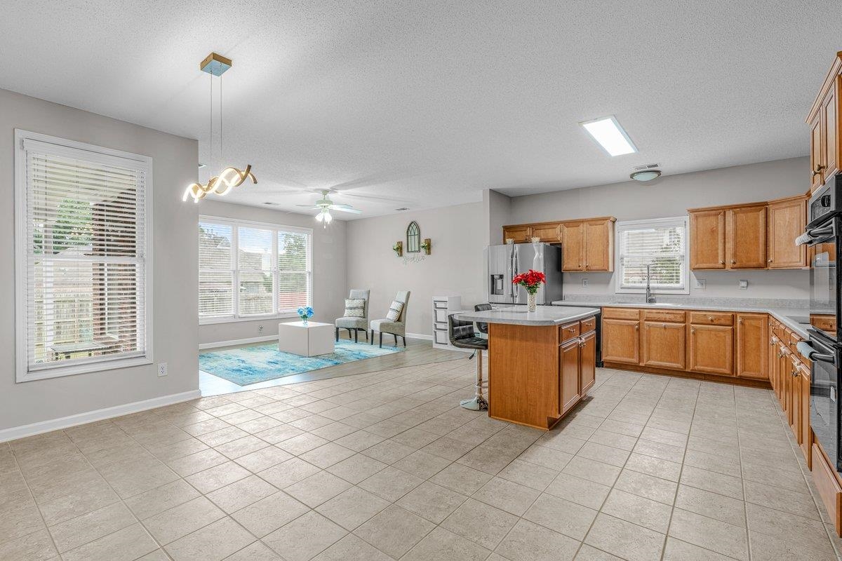 4840 Rainy Pass Road Collierville, TN 38017 - Photo 12 of 30 Spacious open-concept interior featuring light tile flooring, an expansive kitchen with wood cabinetry and a central island, stainless steel appliances, and a bright living area with multiple windows