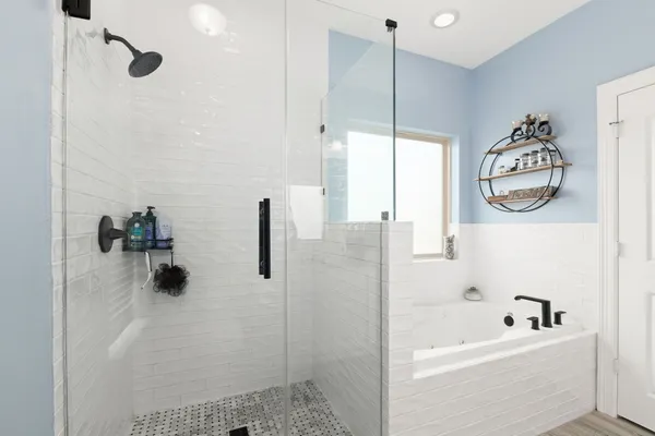 a bathroom with a tub a window and a shower