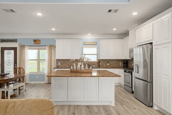 a large kitchen with kitchen island a large counter top stainless steel appliances a sink and cabinets