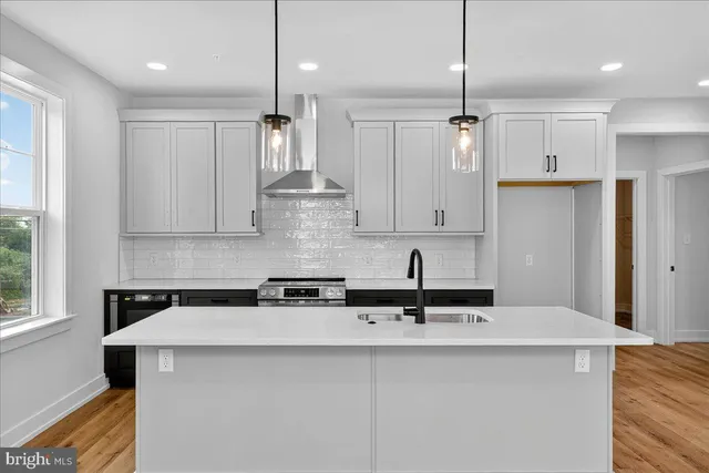 a kitchen with stainless steel appliances a sink a stove a refrigerator a center island and cabinets