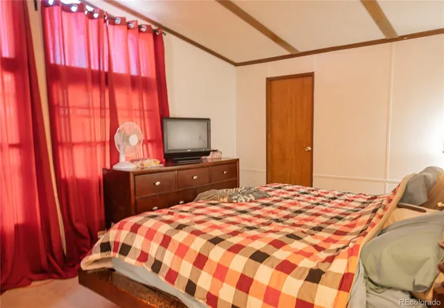 a bedroom with a bed and a flat tv screen on dresser