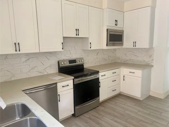 a kitchen with granite countertop white cabinets and white appliances