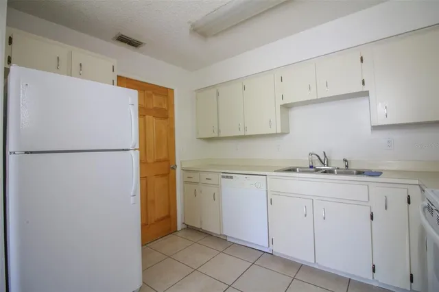 a kitchen with white cabinets and refrigerator