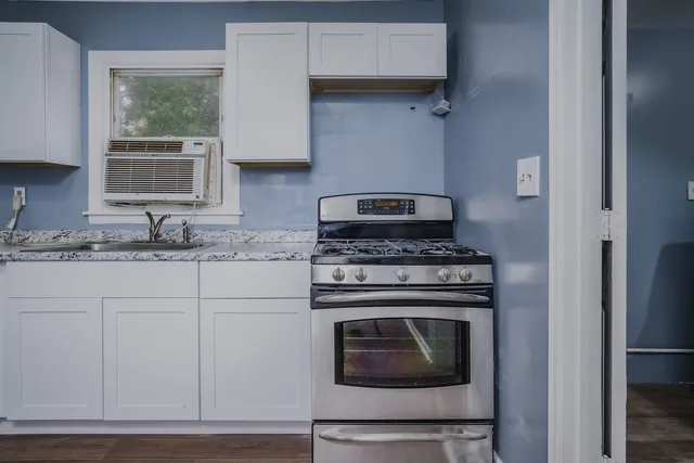 a kitchen with stainless steel appliances granite countertop a refrigerator a sink and white cabinets with wooden floor