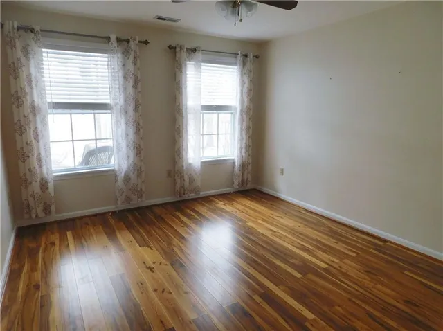 an empty room with wooden floor and windows