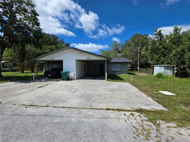 a view of a house with backyard and a tree