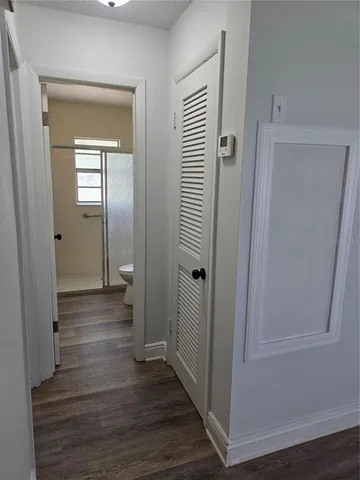 a view of a hallway with wooden floor and closet
