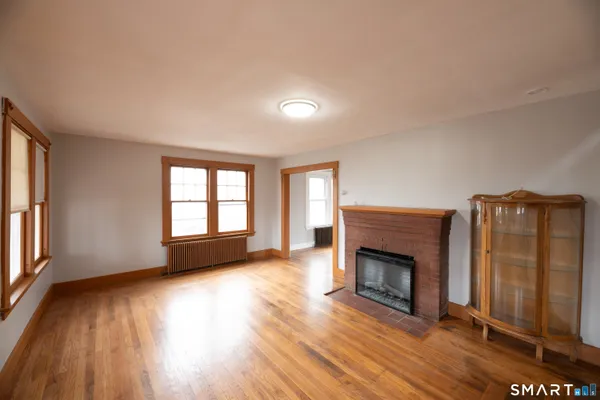 an empty room with wooden floor fireplace and windows