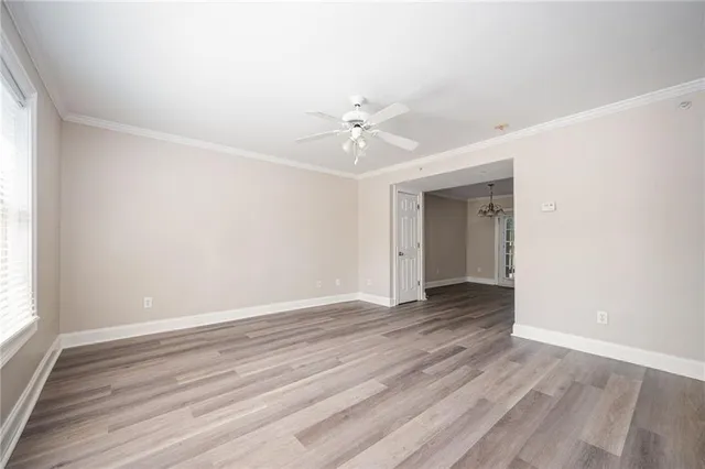 an empty room with wooden floor ceiling fan and windows