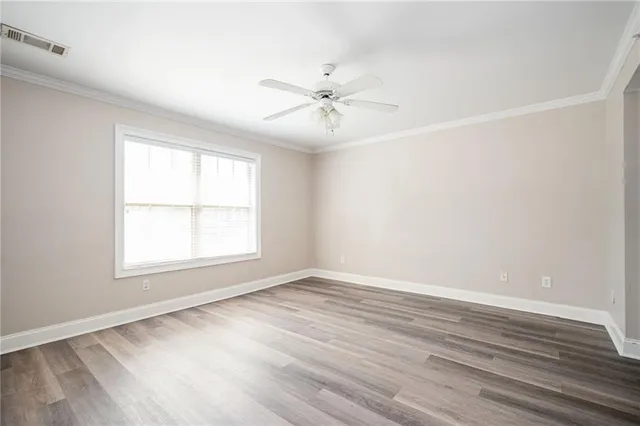 an empty room with wooden floor ceiling fan and windows
