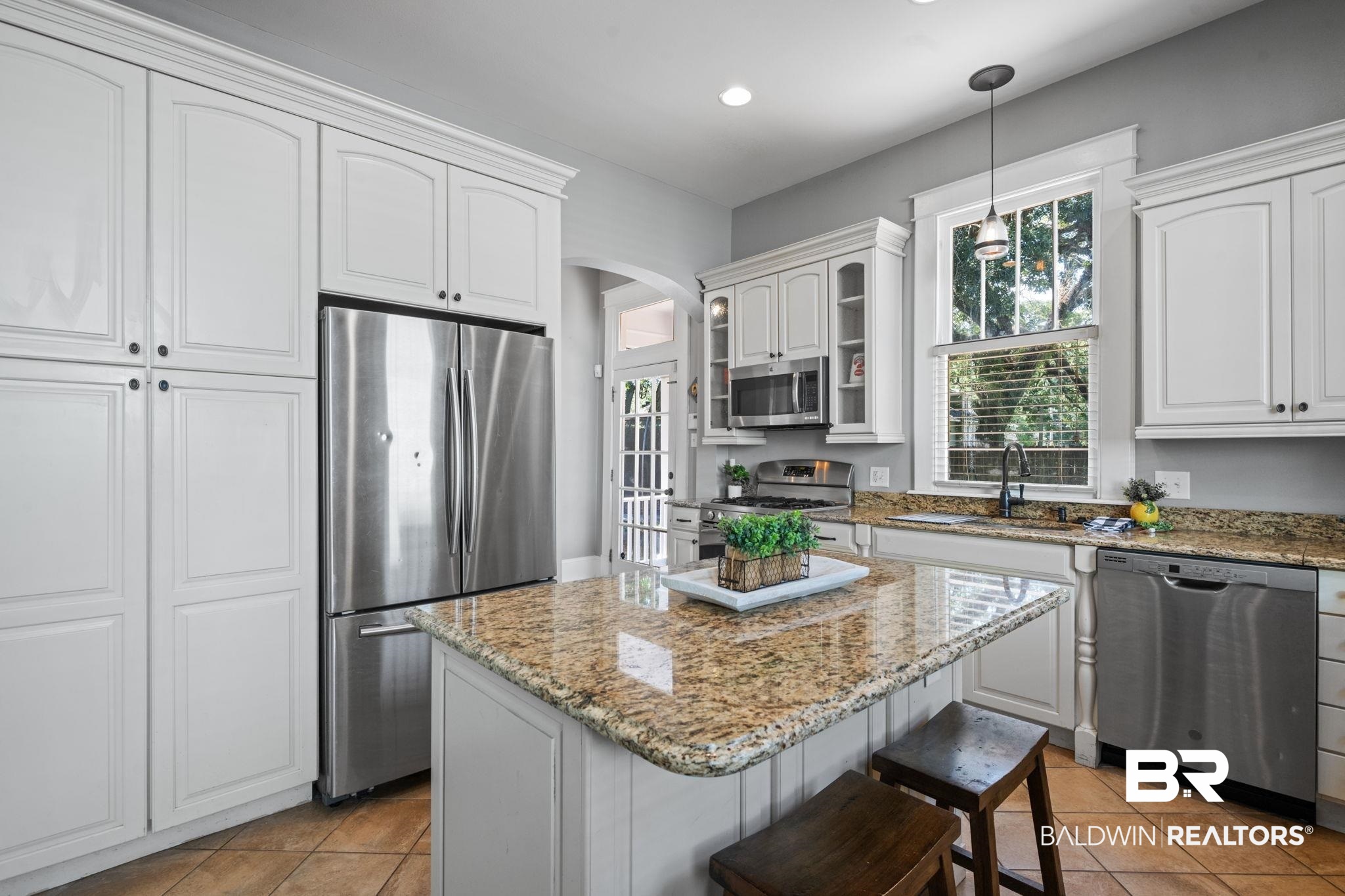 10 South Monterey Street Mobile, AL 36604 - Photo 15 of 45 Kitchen featuring appliances with stainless steel finishes, light stone countertops, a center island, glass insert cabinets, and light tile patterned floors