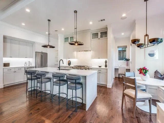 a kitchen with stainless steel appliances kitchen island granite countertop a wooden floor and white cabinets