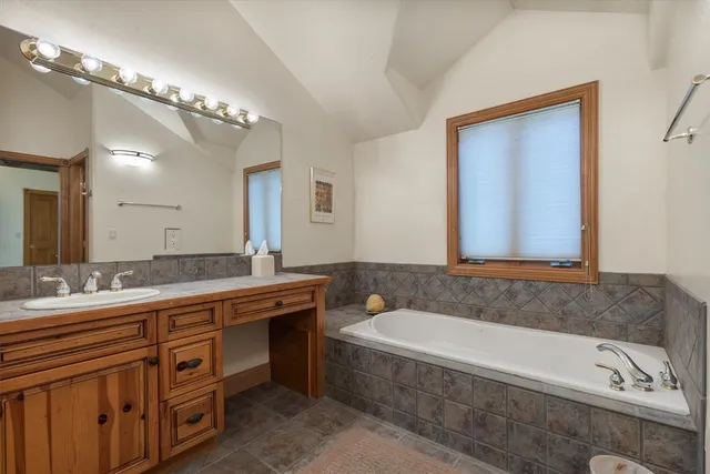 a bathroom with a granite countertop bathtub a double vanity sink and a mirror