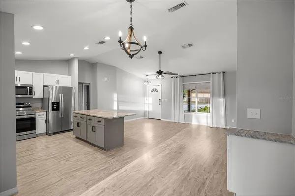 a large kitchen with stainless steel appliances a large counter top a refrigerator a sink and a stove
