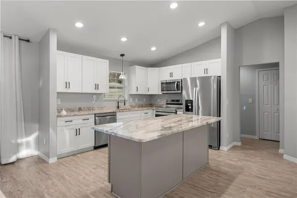 a kitchen with stainless steel appliances granite countertop a refrigerator a stove a sink and white cabinets